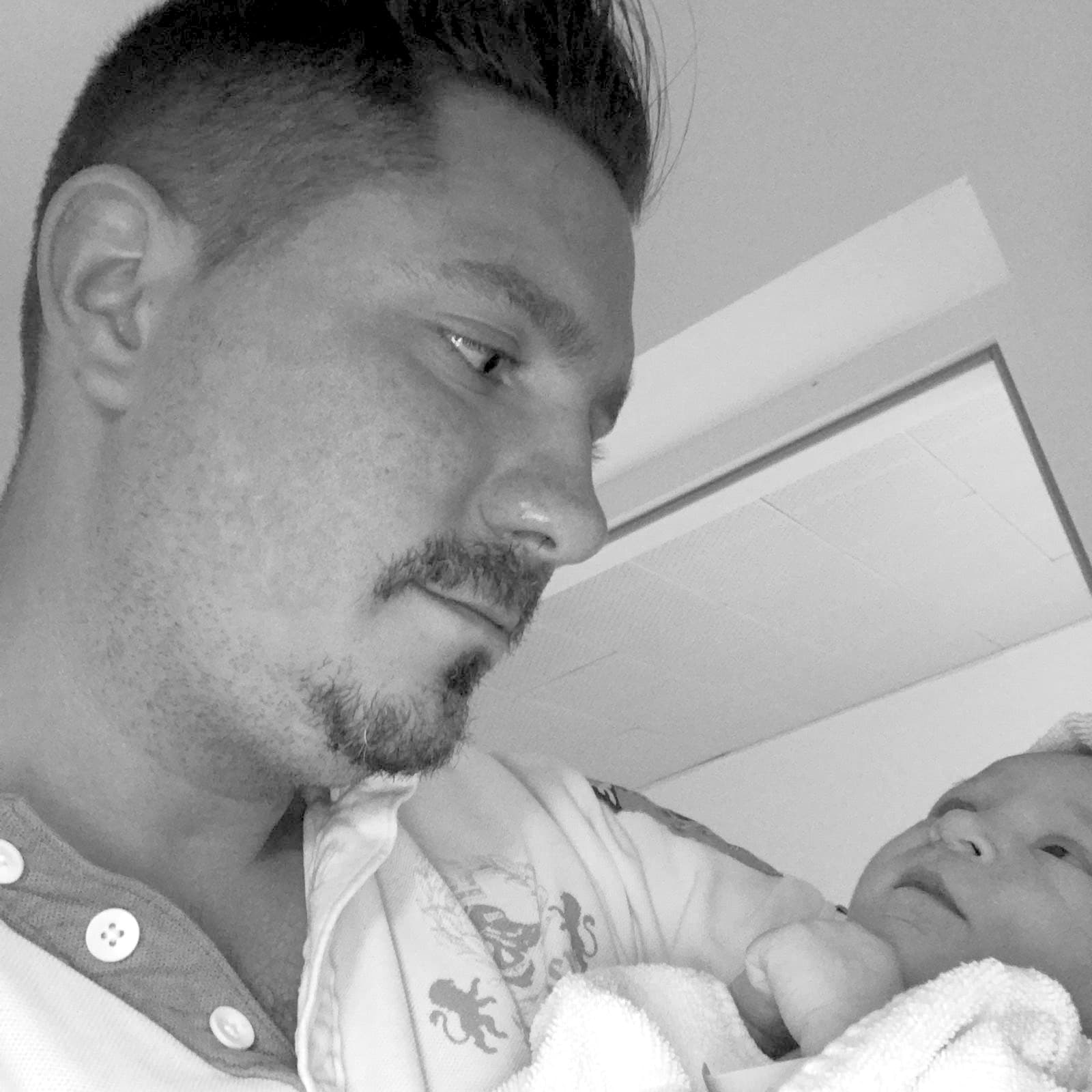 Michael Kolar hält seine neugeborene Tochter Alina im Arm. Schwarz-Weiß-Aufnahme.